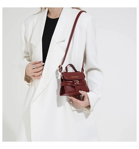 Detail view of wine red crossbody bag featuring litchi texture and gold fashion lettering