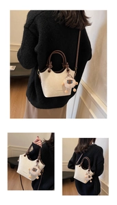 Detail of off-white bucket bag with brown handle and cute plush sheep charm accessory