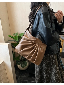 Détail d'un sac cabas plissé marron en similicuir avec un écusson logo rectangulaire chic