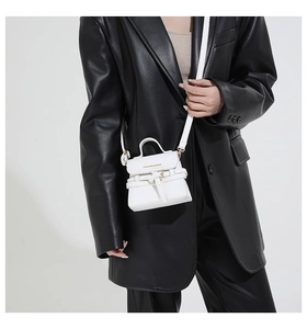 Detailed macro view of white mini crossbody bag with golden hardware and fashion logo