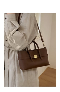 Close-up of retro dark brown litchi pattern leather handbag with gold twist lock hardware