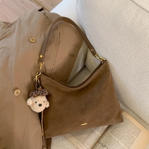 Detail of dark brown suede shoulder bag with cute teddy bear charm and gold metal buckle