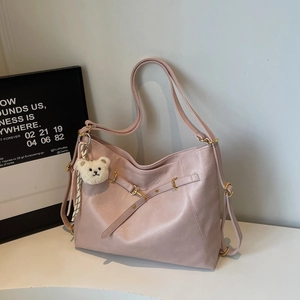 Detailed view of pink tote bag featuring a gold buckle and cute teddy bear charm accessory