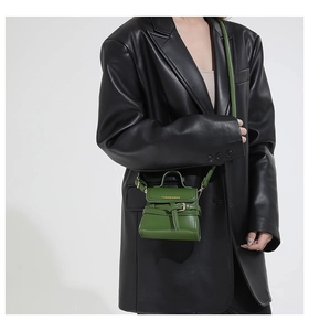 Close-up of retro green leather mini bag worn with a black leather jacket on model
