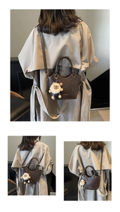 Detailed back view of vintage brown bucket bag with lion plush keychain on beige trench coat