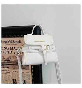 Close-up of off-white mini crossbody bag with gold text detail and fine texture
