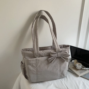 Detailed view of dark grey tote bag featuring a large bow and side elastic pocket