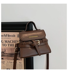 Detailed close-up of brown PU leather handbag with gold hardware and fashion logo