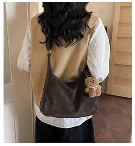 Detail of dark brown matte leather crescent tote bag with cute plush bear charm