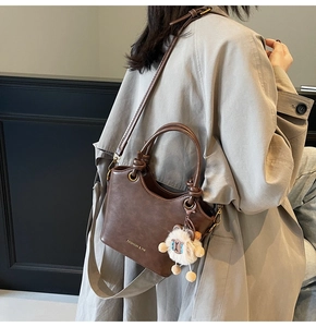 Detail of dark brown PU leather bucket bag with fashion text and white lamb charm accessory