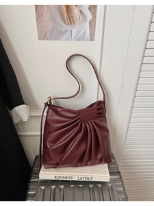 Détail du sac cabas plissé bordeaux avec texture mate et étiquette de marque sur un livre