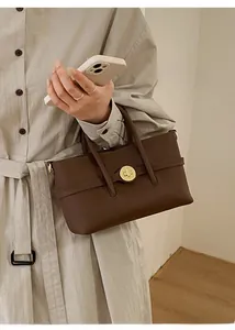Detailed close-up of dark brown leather handbag with golden twist-lock and lychee texture