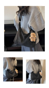 Detail of black pleated hobo bag featuring a brown plush bear charm and wide shoulder strap