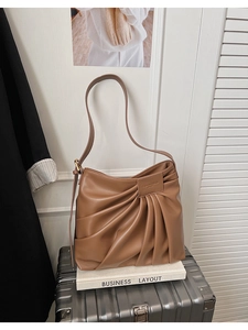 Détail du sac hobo plissé marron caramel avec étiquette mode et texture en cuir souple