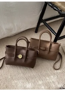 Close-up of litchi grain leather handbags with golden rotary locks in brown and caramel
