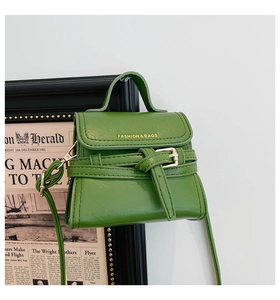 Close-up of avocado green leather bag with gold lettering and metal buckle detail