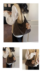 Detail of deep brown suede Hobo bag with black wide strap and teddy bear charm