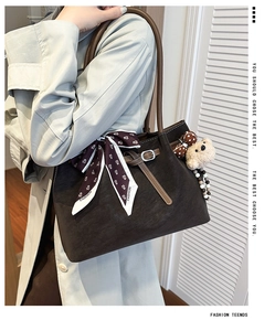 Detail of dark brown suede tote bag featuring a decorative silk scarf and plush bear charm