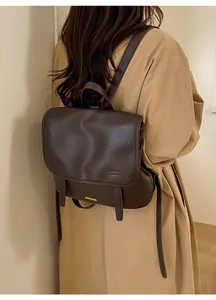 Vista laterale di uno zaino vintage in pelle PU marrone scuro indossato con un trench