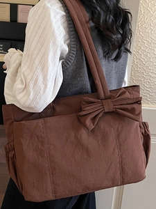 Brown bow tote bag in nylon fabric with large capacity carried by a model