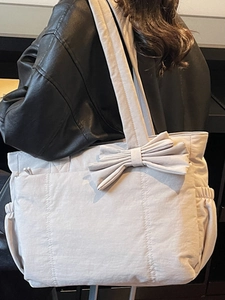 Chic beige tote bag with a bow accent and spacious design for daily fashion and travel