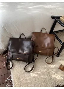 Dettaglio di zaini vintage in pelle color caffè e caramello con logo in metallo dorato