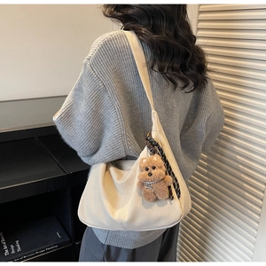 Close-up of beige shoulder tote bag with soft pleated texture and brown plush bear charm