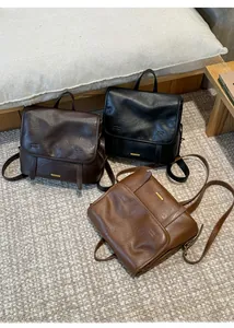 Tre zaini in pelle vintage nero, caffè scuro e marrone chiaro su un tappeto intrecciato