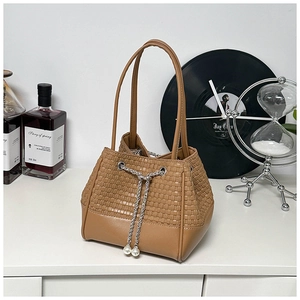Detail of brown woven bucket bag featuring pearl charms and silver chain drawstring closure
