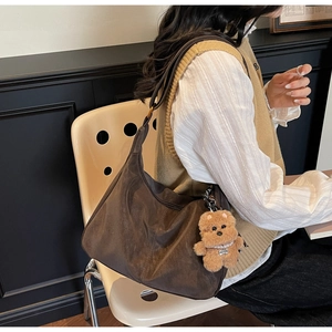 Detailed view of deep brown hobo bag with soft pleated texture and plush bear charm
