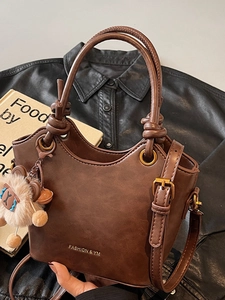 Brown vintage faux leather bucket bag with top handle and plush bear charm accessory