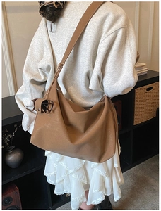 Detailed view of brown soft leather hobo bag with natural folds shown on shoulder