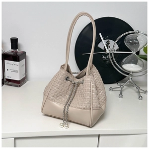Detail of woven beige bucket bag featuring silver chain drawstring and pearl accents