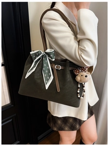 Detail of dark olive green tote bag with floral scarf and brown bear charm on shoulder