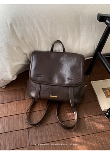 Detail view of vintage dark brown leather backpack with golden nameplate and fine stitching