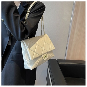 Détail d'un sac à chaîne matelassé beige avec fermoir doré et texture en cuir lisse