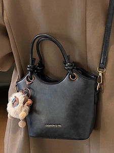 Minimalist black leather bucket bag with top handles and cute plush sheep charm
