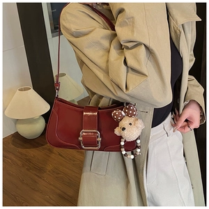 Détail du sac baguette bordeaux avec boucle argentée et breloque ours sur modèle