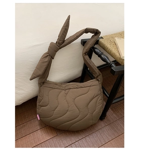 Detail of a brown quilted crossbody bag with stylish knot strap and stitched texture