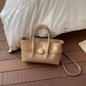 Detail view of beige lychee texture leather handbag with golden round twist lock and handles