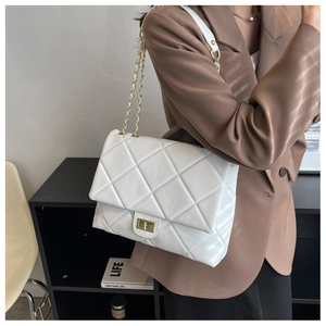 Détail d'un sac matelassé blanc avec chaîne en métal doré et fermoir rotatif rectangulaire