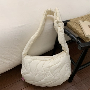 Detail of cream quilted crossbody bag with wave pattern stitching and soft fabric