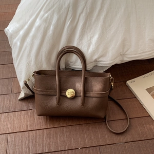Close-up of brown litchi pattern leather bag featuring elegant golden twist lock hardware