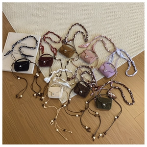 Flat lay of small crossbody bags in eight various colors with silk ribbon straps
