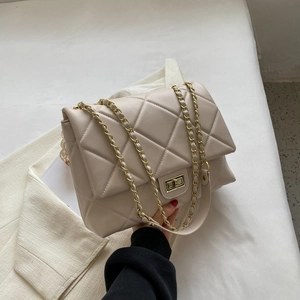 Détail du sac bandoulière beige matelassé avec chaîne dorée et fermoir rotatif en métal
