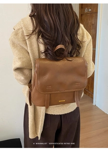 Rear view of a vintage brown leather backpack worn with casual stylish outfit