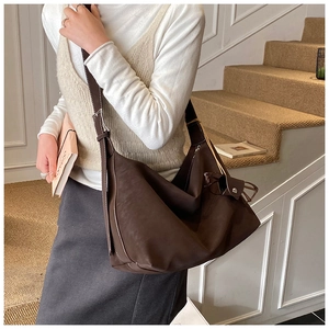 Detail of soft leather shoulder bag with contrast stitching and adjustable buckle strap