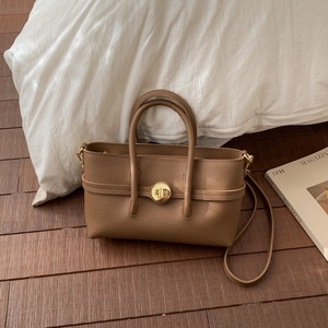 Detail of brown litchi pattern leather bag with golden circular twist lock buckle