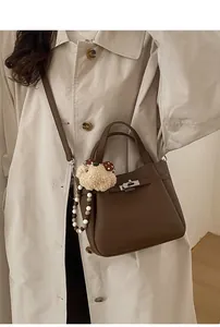 Close-up of deep brown pebbled leather bucket bag with metallic twist lock and charms