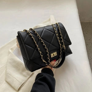 Détail d'un sac à bandoulière matelassé noir avec fermoir doré et bandoulière chaîne
